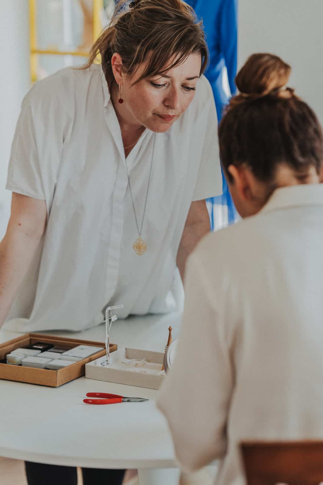 Schmuckdesignerin berät eine Kundin an ihrem Arbeitstisch
